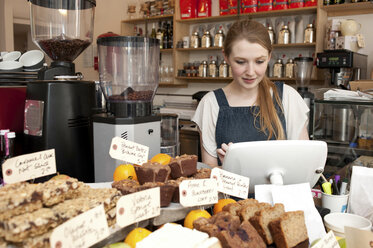 Junge Frau an der Kasse eines Cafés - CUF42086