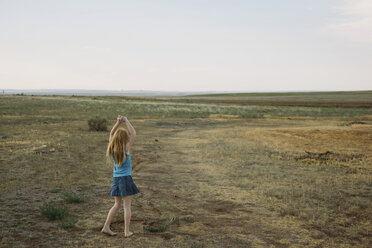 Girl on rural landscape playing alone - CUF42223