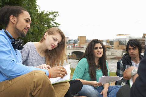 Studenten sitzen im Freien mit Papieren, lizenzfreies Stockfoto