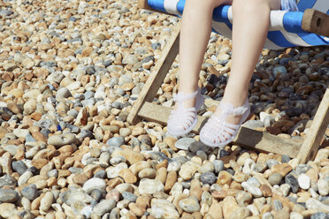 Child with plastic sandals on beach deck chair - CUF42238