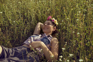 Young woman lying in meadow with flowers in her hair - CUF42355