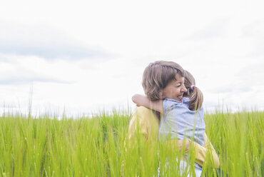 Mutter und Tochter umarmen sich auf einem Feld - CUF42440