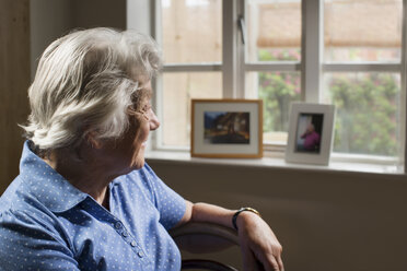 Senior adult woman sitting in room looking out of window - CUF42529