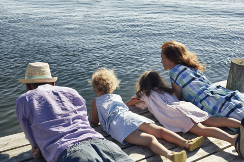 Eltern und Töchter auf dem Steg liegend, Utvalnas, Gavle, Schweden, lizenzfreies Stockfoto