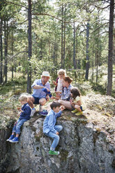 Familie sitzt auf Felsen im Wald und macht ein Picknick - CUF42689
