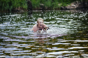 Junger Mann und sein Hund spielen im Fluss - CUF42698