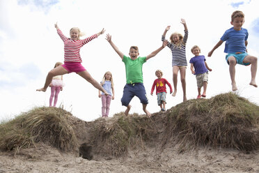 Gruppe von Kindern, die von Sanddünen springen, Wales, UK - CUF42719