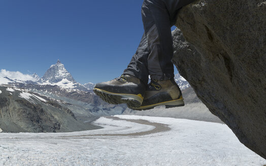 Mann sitzt auf einem Felsen am Matterhorn, Zermatt, Kanton Wallis, Schweiz - CUF42730