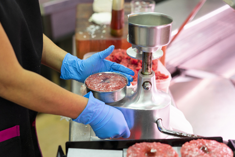 Frau am Marktstand bei der Zubereitung von Hackfleisch, lizenzfreies Stockfoto