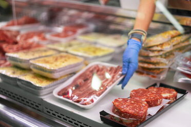 Frau am Marktstand, die verpacktes Fleisch zur Schau stellt - AFVF00773