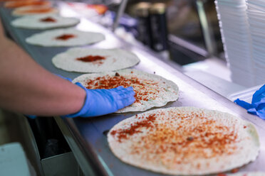 Woman in market stall filling tortilla wraps - AFVF00774