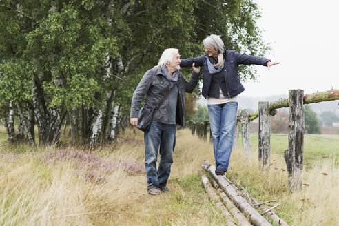 Senior couple, woman balancing on logs - CUF42748