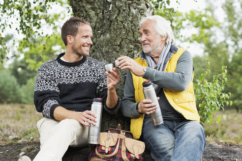 Vater und erwachsener Sohn trinken Kaffee aus einem Flachmann - CUF42767