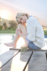 Shy young woman sitting on pier - CUF42807