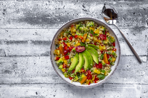 Bowl of bulgur salad with bell pepper, tomatoes, avocado, spring onion and parsley stock photo