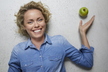 Portrait of happy blond woman with green apple - PNEF00755