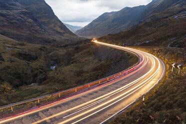 UK, Schottland, Auto-Lichtspuren auf landschaftlich reizvoller Straße durch die Berge im schottischen Hochland in der Nähe von Glencoe in der Abenddämmerung - WPEF00687