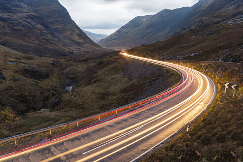 UK, Scotland, car light trails on scenic road through the mountains in the Scottish highlands near Glencoe at dusk - WPEF00687