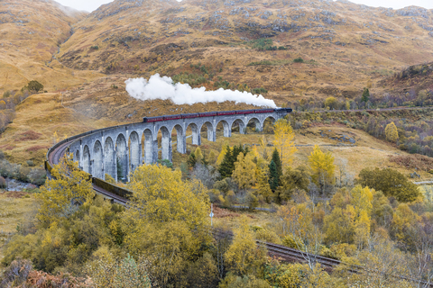 UK, Schottland, Highlands, Glenfinnan-Viadukt mit einem darüber fahrenden Dampfzug, lizenzfreies Stockfoto