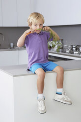 Junge, der in der Küche auf der Seite sitzt, mit Karottenschnurrbart - CUF42884