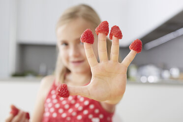 Girl putting raspberries on fingers - CUF42887