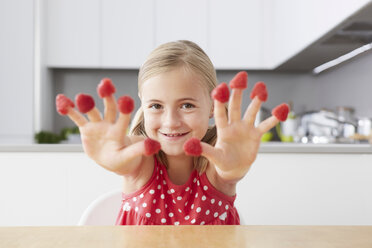 Girl putting raspberries on fingers - CUF42888