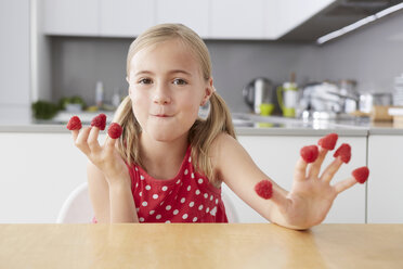 Girl eating raspberries from fingers - CUF42889