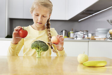 Mädchen balanciert Äpfel auf einer Brokkoliwaage - CUF42892