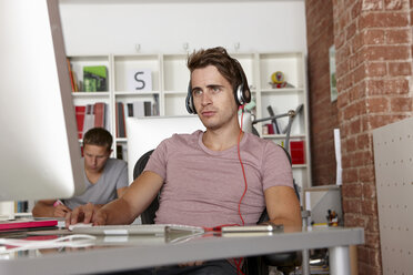 Young man at work wearing headphones - CUF42909