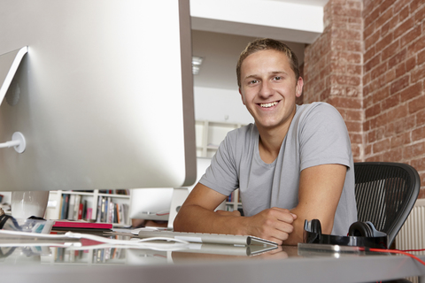 Porträt eines jungen Mannes am Schreibtisch, lizenzfreies Stockfoto