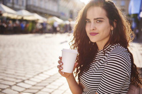 Porträt einer schönen jungen Frau mit Kaffee zum Mitnehmen in der Stadt - ABIF00689