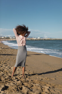 Junge Frau mit Afrofrisur steht am Strand - MAUF01514