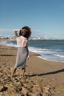 Junge Frau mit Afrofrisur steht am Strand - MAUF01515