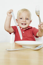 Boy holding cutlery with empty plate - CUF42953