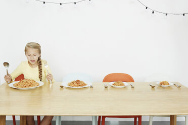 Girl sitting at table with spaghetti and three more plates - CUF42957