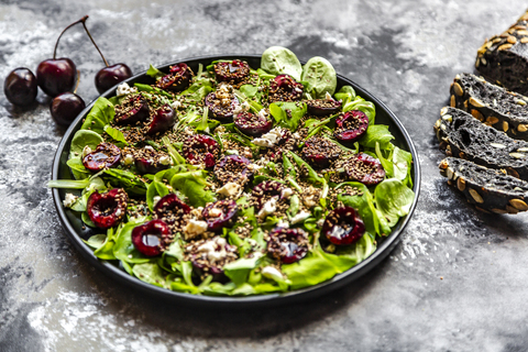 Lamb's lettuce with cherries, feta cheese, roasted sesame and black sepia spelt bread stock photo