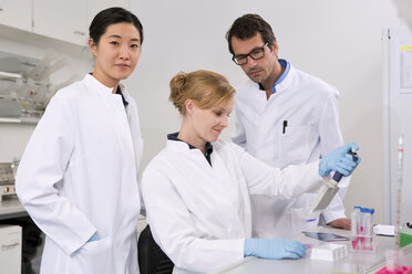 Gruppe von Wissenschaftlern bei Tests im Labor, Pipettieren einer Lösung - CUF43208