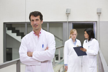 Gruppe von Wissenschaftlern im Atrium mit Blick auf ein Klemmbrett - CUF43211