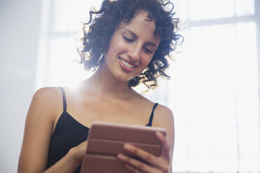 Smiling young woman using digital tablet - HOXF03640