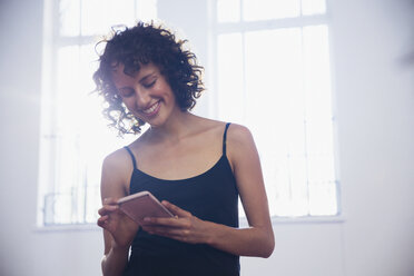 Smiling young female dancer texting with smart phone in dance studio - HOXF03642