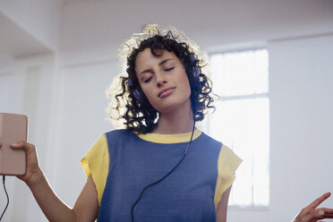 Carefree young female dancer listening to music with headphones and mp3 player - HOXF03662