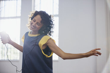 Carefree young female dancer listening to music with headphones and mp3 player - HOXF03666