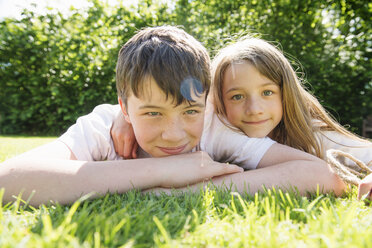 Portrait of brother and sister lying on grass - CUF43313