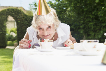 Ältere Frau mit Partyhut schaut in die Kamera, lächelt - CUF43315