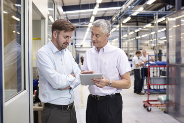 Manager and worker looking at digital tablet in engineering factory - CUF43399