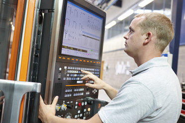 Worker looking at computer monitor in engineering factory - CUF43403