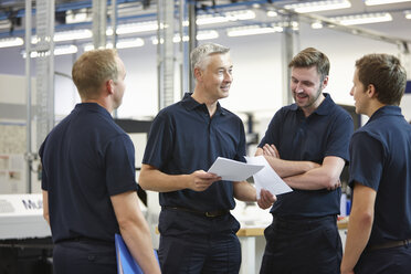 Manager und Arbeiter besprechen Papierkram in einer Maschinenfabrik - CUF43406