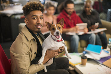 Portrait lächelnder kreativer Geschäftsmann mit Hund im Büro - CAIF20998