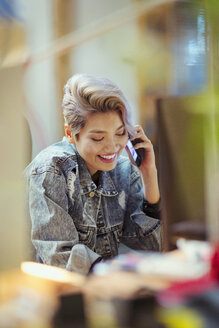 Lächelnde junge Frau, die mit einem Smartphone telefoniert - CAIF21022