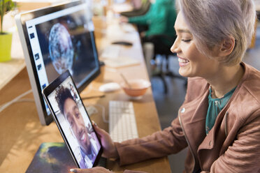 Kreative Geschäftsfrau im Videochat mit einem Kollegen auf einem digitalen Tablet im Büro - CAIF21051